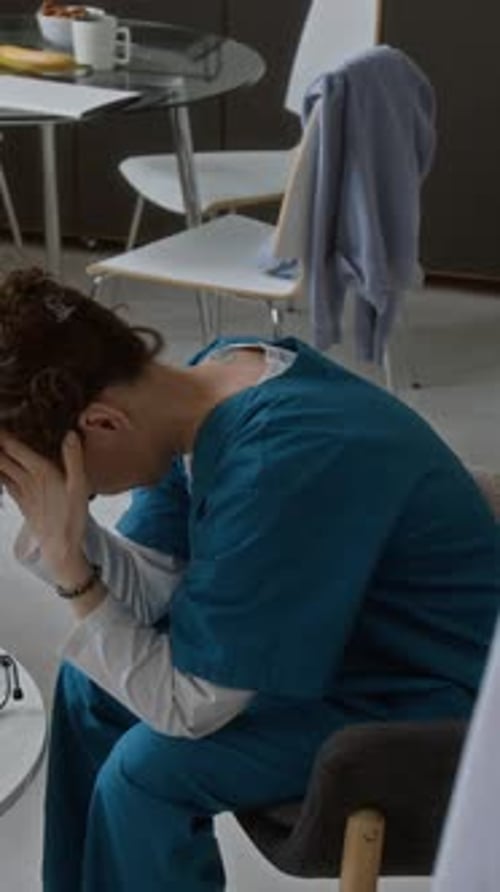 Distraught Woman in Scrubs Sitting in Break Room