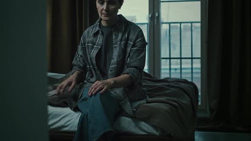 Sad Woman Sits on Bed Looking out Window