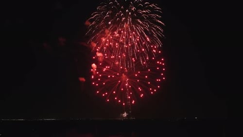 Exploding Fireworks over a Dark Cityscape at Night
