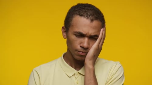 Young Adult Looking Concerned on Yellow Background
