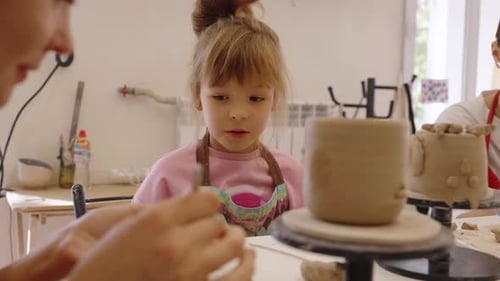 A Young Girl Learns Pottery Skills in a Creative Workshop Setting