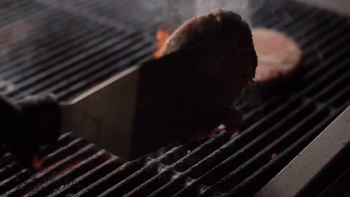 Chef Cooking Beef Patty for Burger on Hot Grill and Flip the Cutlet with a Spatula