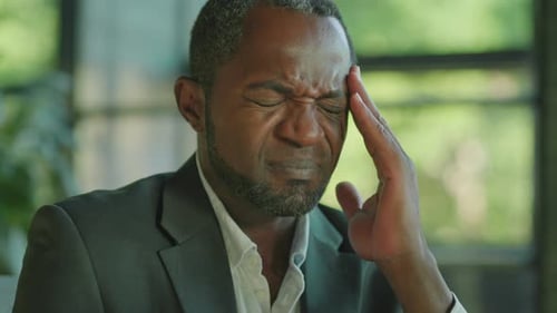 Man in Suit Massaging Temples Due to Headache
