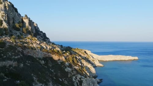 Aerial view flying along the rocky coastline of Rhodes, sunny evening in Greece