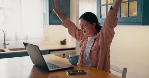 Woman Cheers at Laptop in Sunny Home