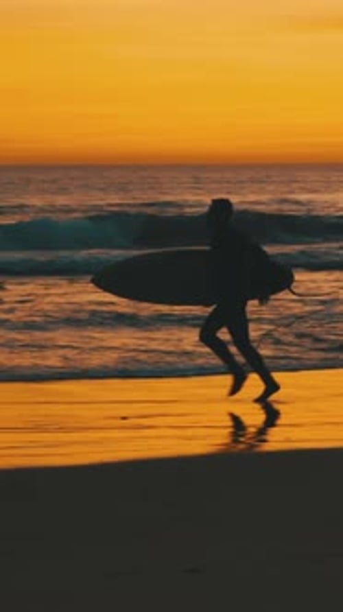 Silhouette of Man Running with Surfboard at Sunset