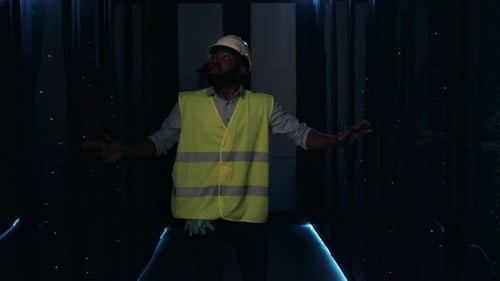 A Construction Worker Wearing a Safety Vest is Seen in a Corridor with Dim Lighting and Shadows