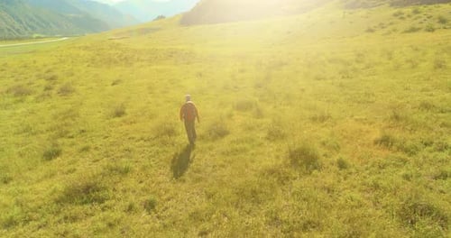 Flight Over Backpack Hiking Tourist Walking Across Green Mountain Field