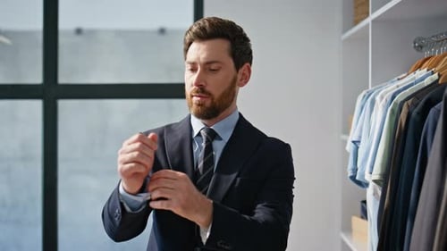 Man Adjusts Suit Cuffs in Modern Walk-In Closet