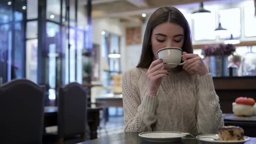 Woman Sipping Coffee and Smiling in a Cafe