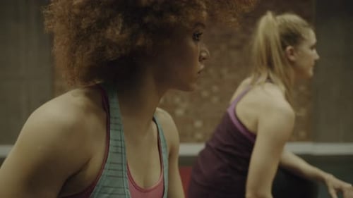 Two adult women exercising with weights in gym