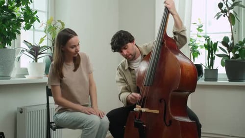 Handsome Man Teaches a Woman to Play the Double Bass
