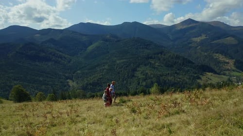 Parents and kids walking on mountain grass enjoying scenic rocky woods view