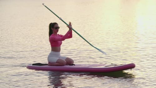 Woman Rowing on Paddle Board During Sunset Over Lake