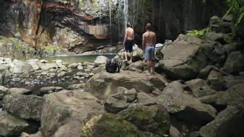 Two men observe Levada das 25 Fontes jungle waterfall in Madeira Portugal