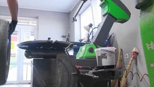 Person Standing on Tire in Garage Watching Automotive Wheel System