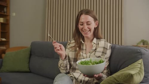 Woman Smiling and Eating Fresh Salad at Home