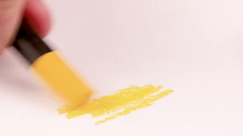 Zeichnen mit einem gelben Farbstift auf einem Blatt Papier.