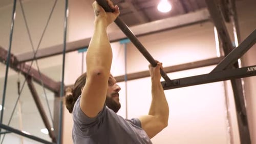 Determined man focuses on pull up strength training workout in gym