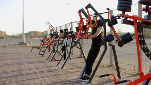 Caucasian Athletic Man Sweating Profusely Training His Back and Arms on the OpenAir Fitness