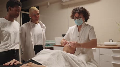 Woman Receiving Facial Treatment Watched by Two Women