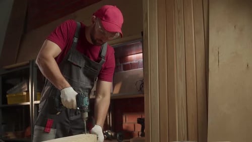 A Skilled Craftsman Utilizes a Drill to Construct Wooden Projects in a Wellorganized Workshop The