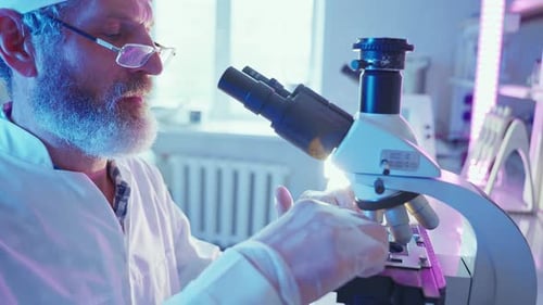 Scientist Examining Sample Through a Microscope in Lab