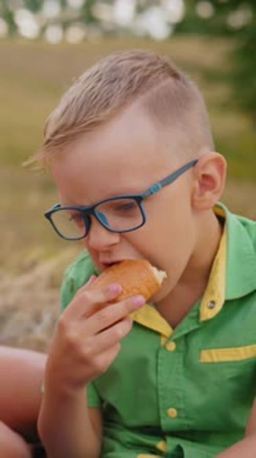 Siblings Enjoying Pastries Outdoors in Open Field