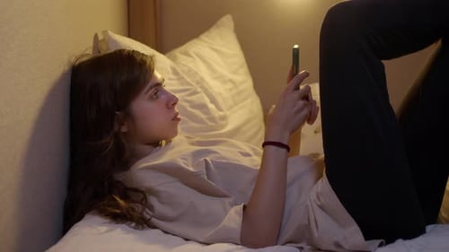 Woman Browsing Cellphone While Lying in Bed
