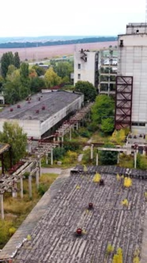 Abandoned factory with many ruined buildings. Old brick thick pipe on empty plant