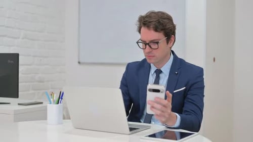 Man Uses Phone at Modern Office Desk