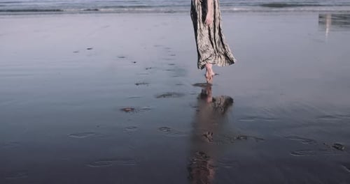 Young adult female running on beach by the sea in dress