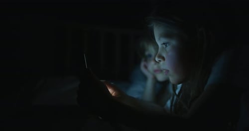 Young Girl Uses Tablet in Dark Bedroom at Night