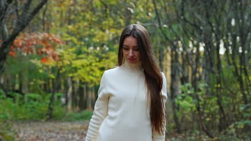 Young pretty woman walking in autumn forest. Portrait of cute lady walking in park.