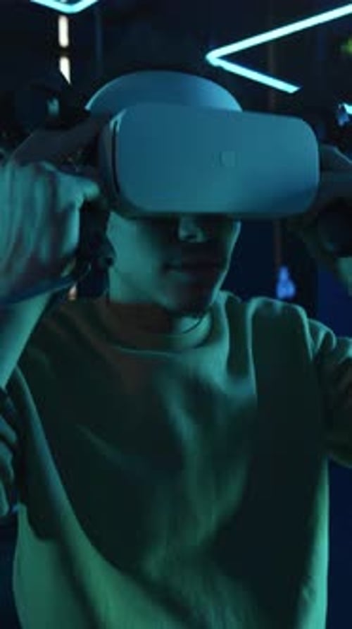 Portrait of Middle Eastern Gamer with AR Headset and Controllers in Dark Arena