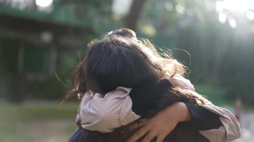 Two female friends hugging each other at park. Happy Women embrace reunion outdoors
