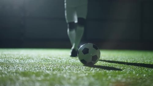 Soccer Player Kicking Ball on Field at Night