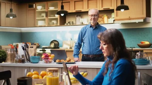 Couple in Kitchen Using Tablet and Laptop