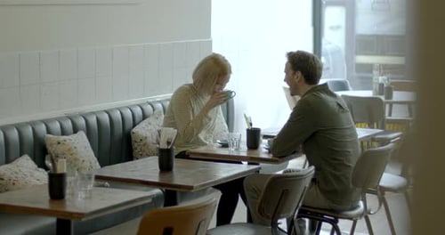 Young Adult couple having a good time together in cafe and drinking coffee at table