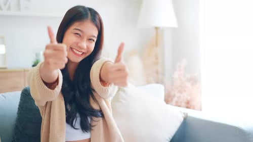 Young Woman Gives Thumbs Up on Couch