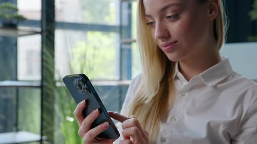 Smiling woman using smartphone indoors during the day