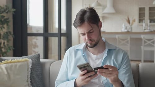 Young Adult Using Phone and Credit Card at Home