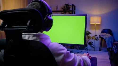 Gamer Using Computer with Green Screen at Night