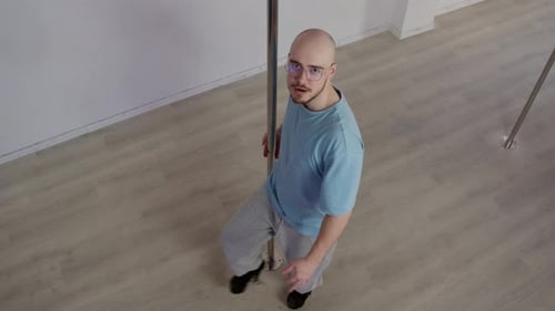 A Man is Seen in a Dance Studio with a Pole Fixed Into the Floor He Dances Around It in a Sensual