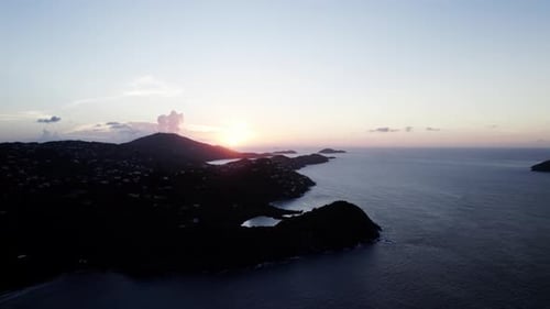 Gorgeous view of sunset calm waters gradient golden sky white clouds homes in the foreground on moun