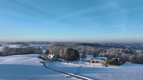 Aerial view of a serene winter landscape featuring snowcovered fields and a distant forest under a