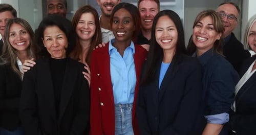Trabajadores multigeneracionales sonriendo frente a una cámara dentro de una oficina comercial: multirraciales,