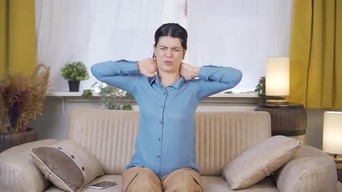 Woman Massaging Stiff Neck on Sofa at Home