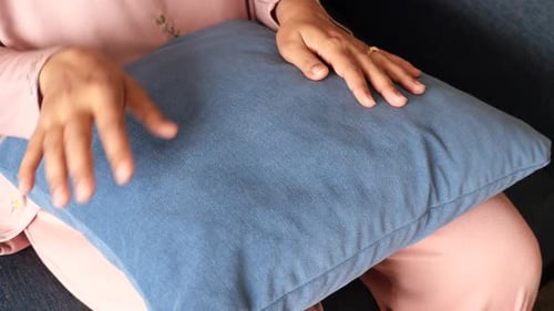 Hands Resting on Blue Pillow at Home