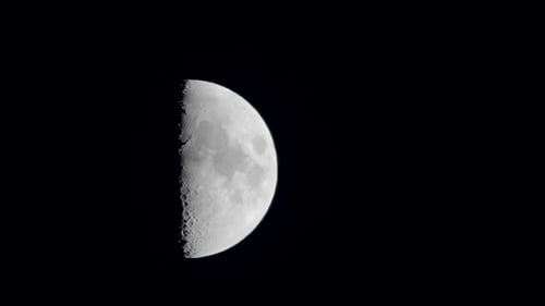 A shot of a first quarter moon slowly rising from up in the sky in Tokyo, Japan.